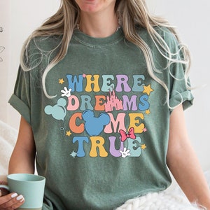 May include: Green t-shirt with a colorful graphic that says "Where Dreams Come True" with Mickey Mouse ears, a castle, and stars.