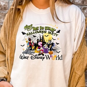 May include: White t-shirt with a colorful graphic of Mickey's Not So Scary Halloween Party at Walt Disney World. The graphic features Mickey Mouse, Minnie Mouse, Goofy, Donald Duck, and other Disney characters in Halloween costumes.