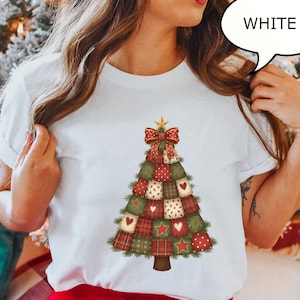 May include: White t-shirt featuring a Christmas tree design. The tree is composed of patchwork squares in red, green, and cream, adorned with hearts, stars, and polka dots. A red bow and gold star top the tree. The word "WHITE" is in a speech bubble.