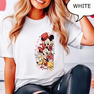 Puede incluir: Camiseta blanca con un gr&aacute;fico colorido de Mickey Mouse, Minnie Mouse y Pluto. Mickey Mouse lleva un sombrero de copa rojo, Minnie Mouse tiene un lazo rojo y Pluto tiene un collar rojo. La palabra "WHITE" est&aacute; en un bocadillo.