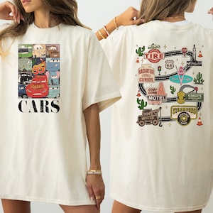 Puede incluir: Una camiseta blanca con un dise&ntilde;o tem&aacute;tico de Cars. La parte delantera de la camiseta presenta un collage de personajes de Cars, incluyendo Rayo McQueen, Mate y otros. La parte posterior de la camiseta presenta un mapa de carreteras con varios puntos de referencia de la pel&iacute;cula Cars, incluyendo Radiador Springs, el Motel Cozy Cone y la tienda de excedentes de Sarge.