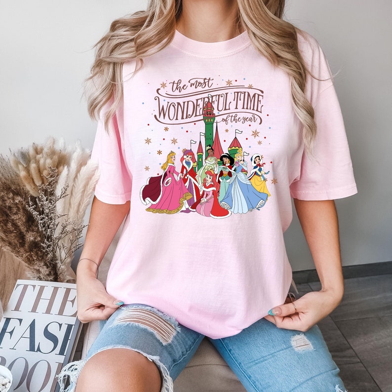 May include: Pink t-shirt with a graphic of Disney princesses in front of a castle with the text "the most wonderful time of the year".
