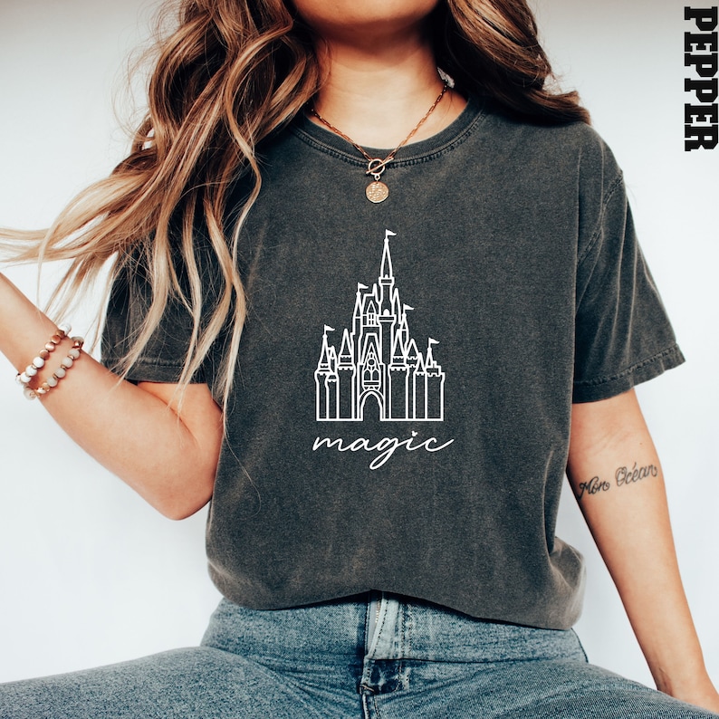May include: A dark gray t-shirt with a white outline of Cinderella's castle and the word "magic" underneath.