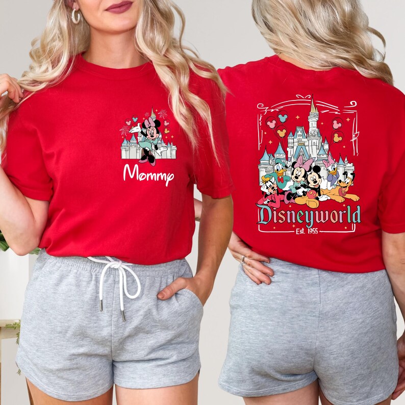 May include: Two red t-shirts with a Disney World theme. One shirt features Mickey Mouse and Minnie Mouse in front of Cinderella's Castle with the text "Disneyworld Est. 1955". The other shirt features Minnie Mouse and the text "Mommy".