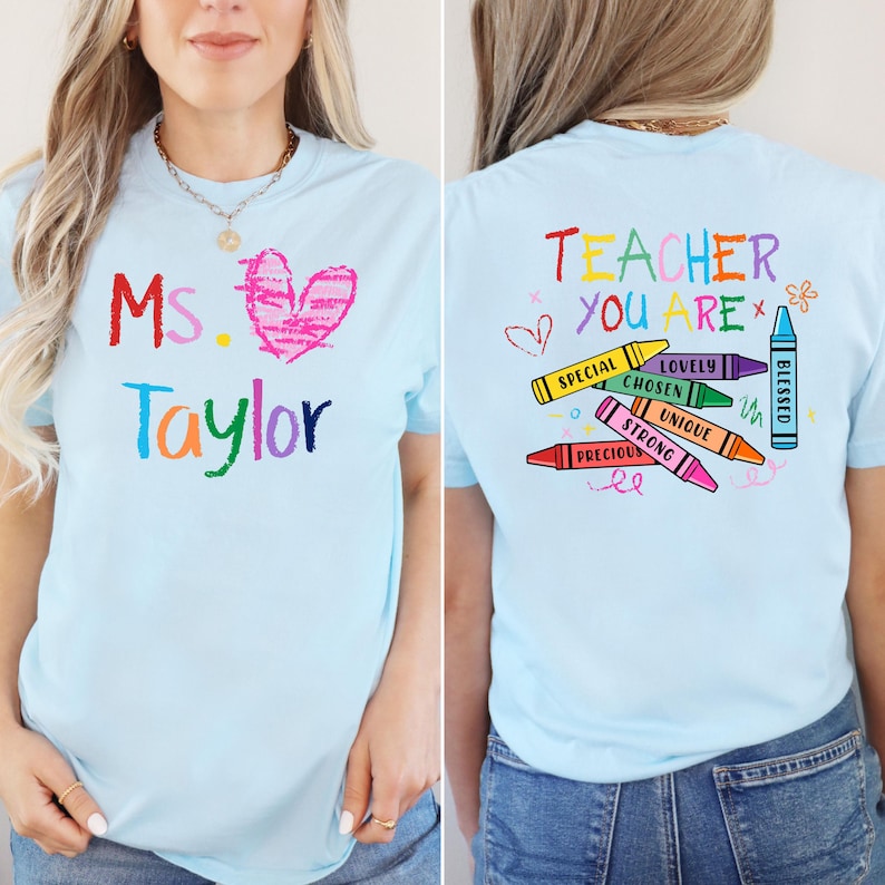 May include: Light blue t-shirt with the text "Ms. Taylor" and a pink heart on the front. The back of the shirt says "Teacher You Are" with crayon graphics and the words "Special, Lovely, Chosen, Unique, Strong, Precious, Blessed."