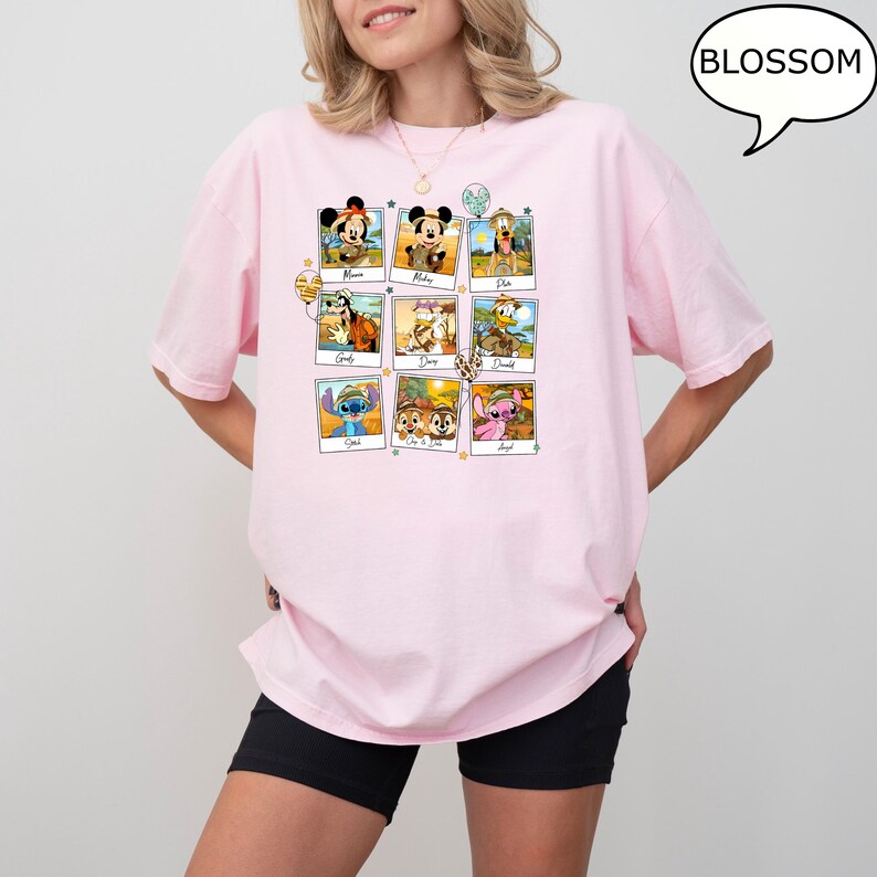 Puede incluir: Camiseta rosa con un gr&aacute;fico de nueve personajes de Disney en marcos de fotos. Los personajes incluyen a Mickey Mouse, Pluto, Donald Duck, Stitch y Chip y Dale. El texto "Blossom" est&aacute; en un bocadillo de di&aacute;logo en la esquina superior derecha de la imagen.
