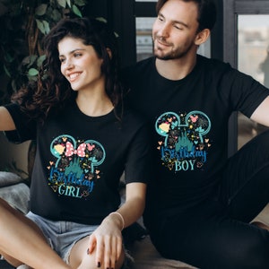 Puede incluir: Dos camisetas negras con un estampado gr&aacute;fico de un castillo, fuegos artificiales y orejas de Mickey Mouse. El texto en las camisetas dice "Birthday Girl" y "Birthday Boy".