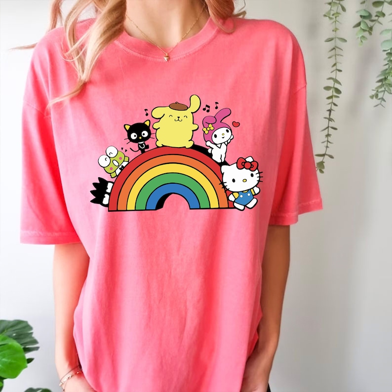 Pode incluir: Camiseta rosa com um arco-&iacute;ris e personagens de desenhos animados, incluindo Hello Kitty, My Melody, Keroppi e Badtz-Maru.