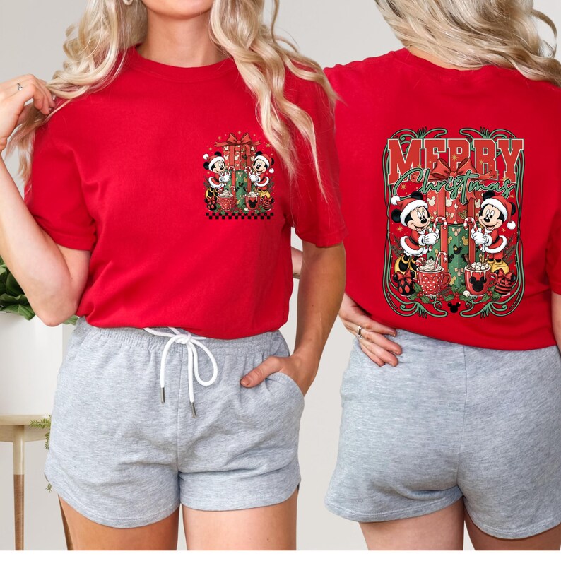 May include: Red t-shirt with a Christmas design featuring Mickey and Minnie Mouse. The front has a small pocket design, while the back displays "Merry Christmas" with the characters. The shirt is short-sleeved.