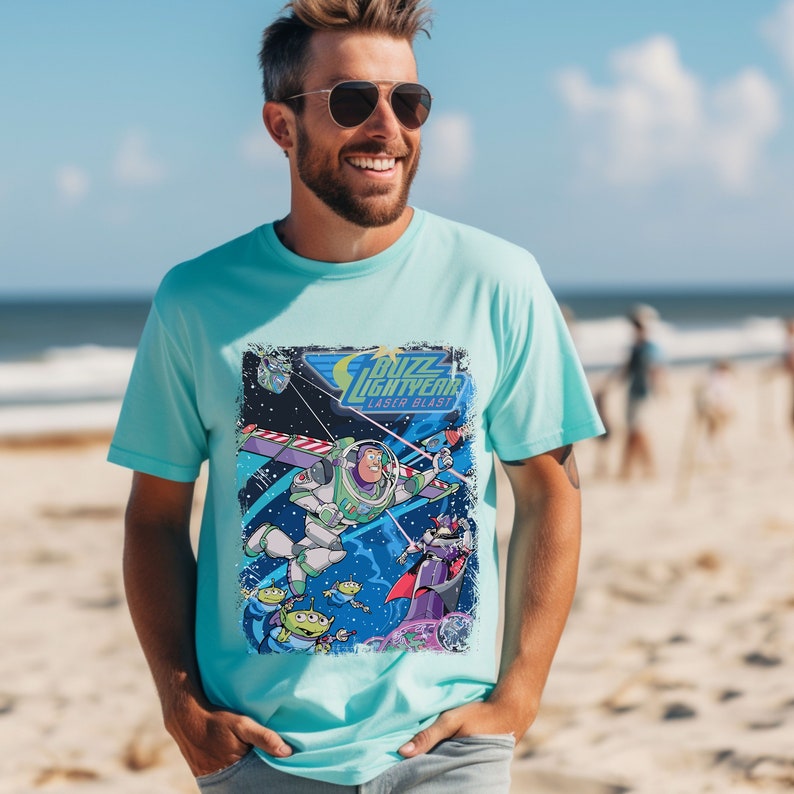May include: A light blue t-shirt with a distressed graphic print of Buzz Lightyear from the Toy Story franchise. The graphic features Buzz Lightyear flying in space with other characters from the movie. The text "Buzz Lightyear Laser Blast" is printed on the graphic.