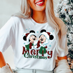May include: White t-shirt with a red and green plaid Mickey Mouse and Minnie Mouse design. The text "Merry Christmas" is written in red and green plaid.