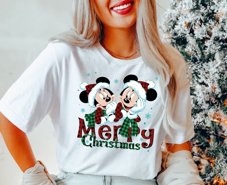 May include: White t-shirt with a red and green plaid Mickey Mouse and Minnie Mouse design. The text "Merry Christmas" is written in red and green plaid.