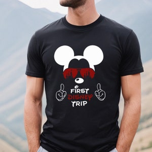 May include: Black t-shirt with a white Mickey Mouse head wearing red sunglasses and the text "First Disney Trip" in red.
