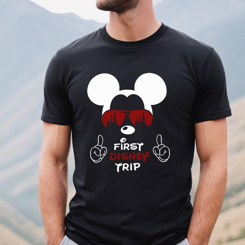 May include: Black t-shirt with a white Mickey Mouse head wearing red sunglasses and the text "First Disney Trip" in red.