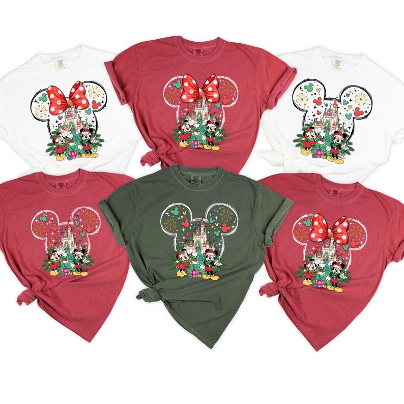 Puede incluir: Cinco camisetas con un dise&ntilde;o de Mickey Mouse con tem&aacute;tica navide&ntilde;a. Las camisetas son de color rojo, blanco y verde. El dise&ntilde;o presenta a Mickey Mouse y Minnie Mouse frente al Castillo de Cenicienta con fuegos artificiales en el fondo.