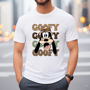 May include: White t-shirt featuring a cartoon image of Goofy wearing a safari hat. The text "GOOFY GOOFY GOOFY GOOFY" is printed on the shirt in a leopard print pattern.