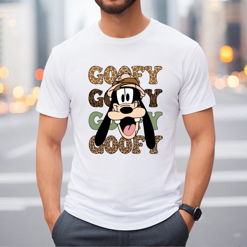 May include: White t-shirt featuring a cartoon image of Goofy wearing a safari hat. The text "GOOFY GOOFY GOOFY GOOFY" is printed on the shirt in a leopard print pattern.