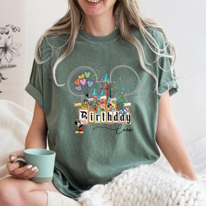 Puede incluir: Una camiseta verde con un gr&aacute;fico de Mickey Mouse y otros personajes de Disney frente al Castillo de Cenicienta. El texto "Birthday Crew" est&aacute; impreso en la camiseta.