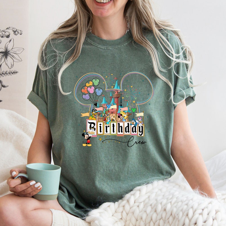 Puede incluir: Una camiseta verde con un gr&aacute;fico de Mickey Mouse y otros personajes de Disney frente al Castillo de Cenicienta. El texto "Birthday Crew" est&aacute; impreso en la camiseta.