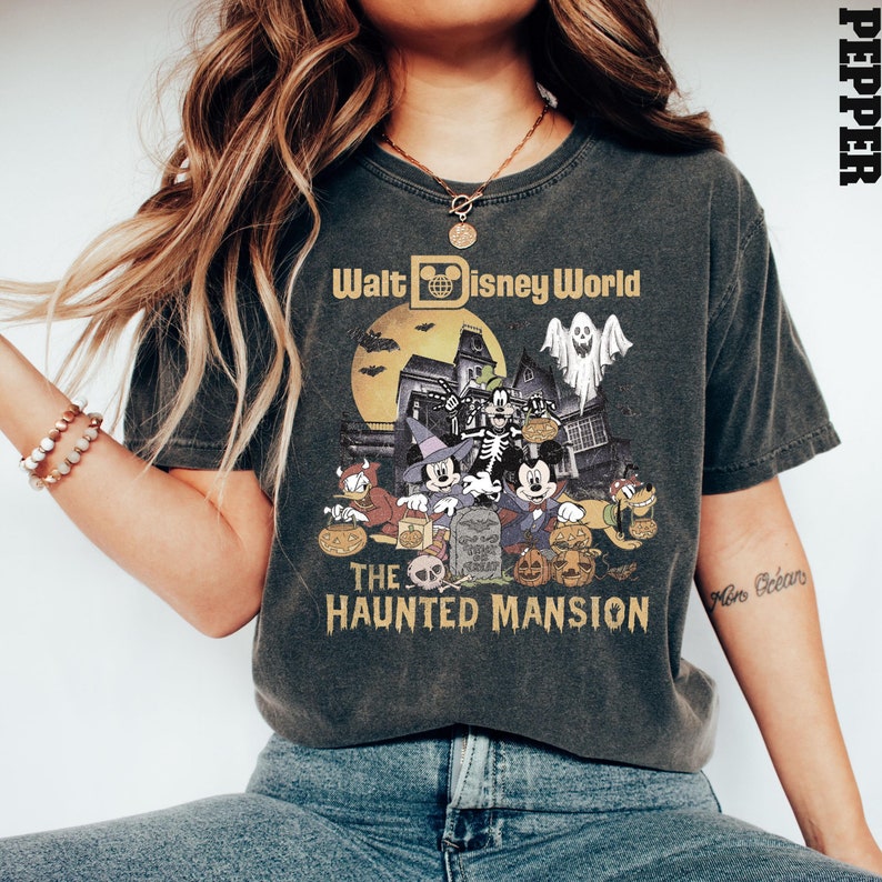 Puede incluir: Una camiseta negra con un gr&aacute;fico de estilo vintage de Mickey Mouse y sus amigos frente a la Mansi&oacute;n Encantada en Walt Disney World. El texto "Walt Disney World" y "The Haunted Mansion" est&aacute; impreso en la camiseta.