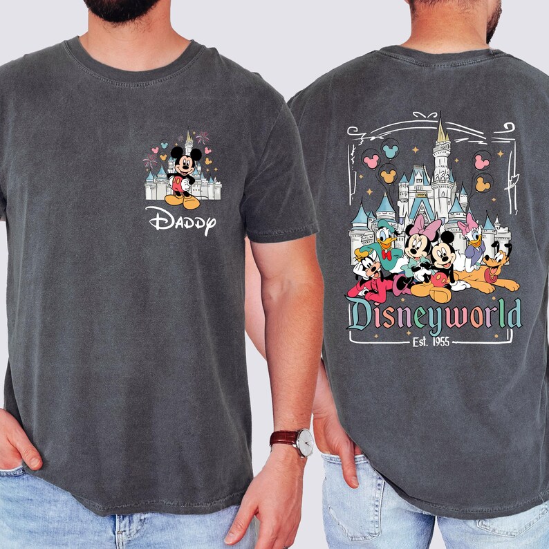 May include: A dark gray t-shirt with a vintage look. The front of the shirt has a cartoon image of Mickey Mouse in front of Cinderella's Castle with the word "Daddy" below. The back of the shirt has a cartoon image of Mickey Mouse, Minnie Mouse, Donald Duck, Goofy, Pluto, and Daisy Duck in front of Cinderella's Castle with the words "Disneyworld Est. 1955".