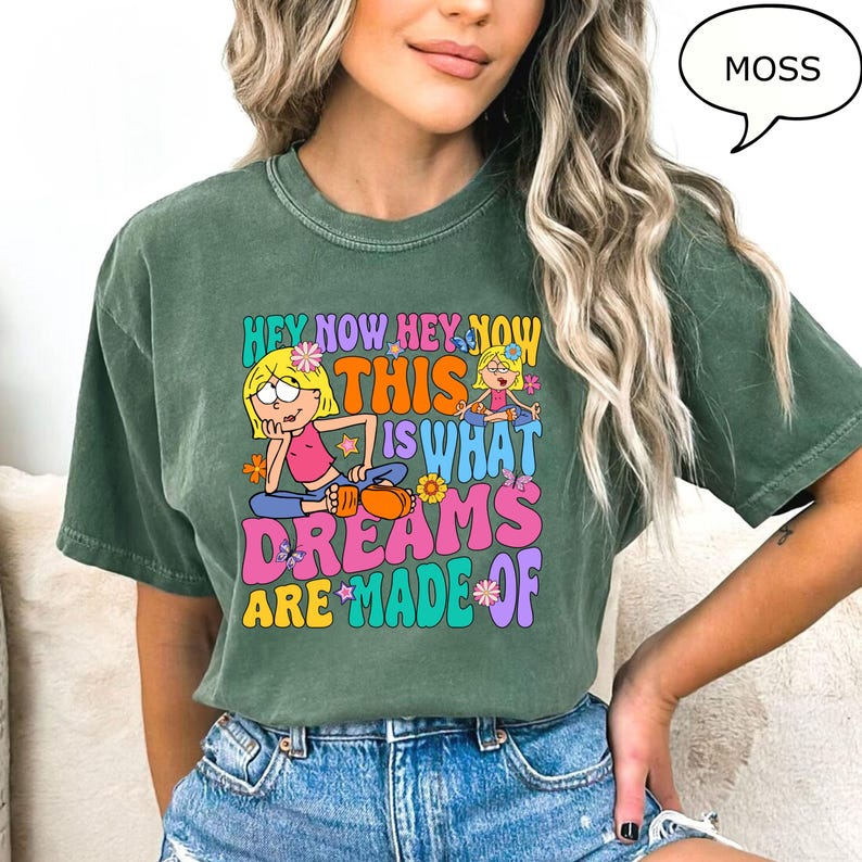Może przedstawiać: Zielona koszulka z kr&oacute;tkim rękawem z kolorowym nadrukiem graficznym, na kt&oacute;rym widnieje napis "Hey Now Hey Now This Is What Dreams Are Made Of". Grafika przedstawia dwie kresk&oacute;wkowe dziewczyny i kwiaty.