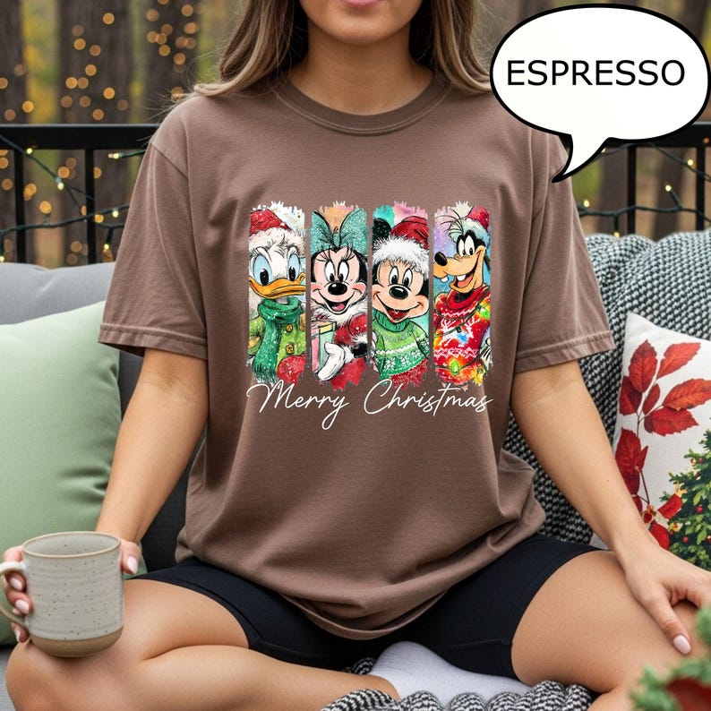 Puede incluir: Camiseta marr&oacute;n con un dise&ntilde;o navide&ntilde;o con el Pato Donald, Minnie Mouse, Mickey Mouse y Goofy. Las palabras "Merry Christmas" est&aacute;n escritas debajo de los personajes. La camiseta es de corte holgado y de color marr&oacute;n.