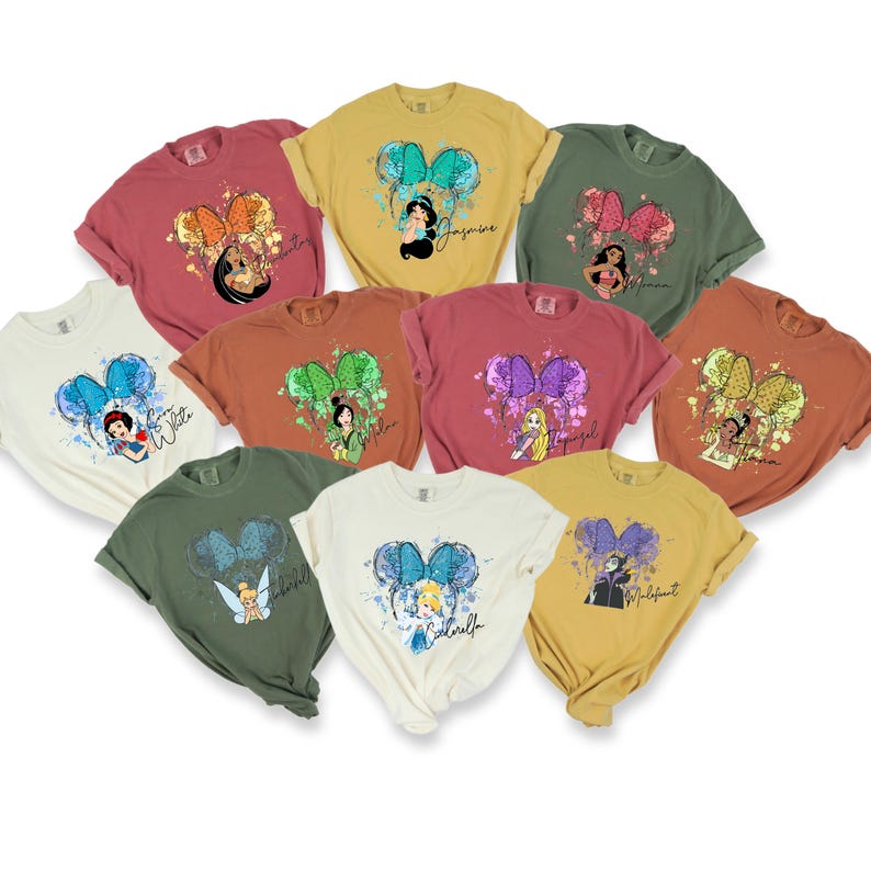 Peut inclure: Dix t-shirts diff&eacute;rents repr&eacute;sentant des princesses Disney avec leurs noms imprim&eacute;s sur chaque t-shirt. Les t-shirts sont de couleurs diff&eacute;rentes et ont un effet aquarelle avec un n&oelig;ud sur chaque t-shirt.