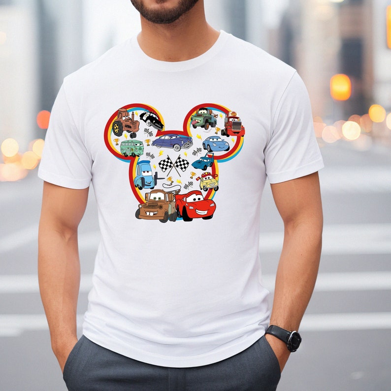 Puede incluir: Camiseta blanca con un dise&ntilde;o de cabeza de Mickey Mouse rojo, amarillo y azul con varios personajes de Cars, incluyendo Rayo McQueen, Mate y Mate remolcador.