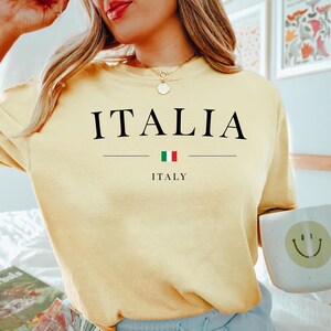 May include: A yellow t-shirt with the word "ITALIA" printed in black letters, with the Italian flag and the word "ITALY" printed below.