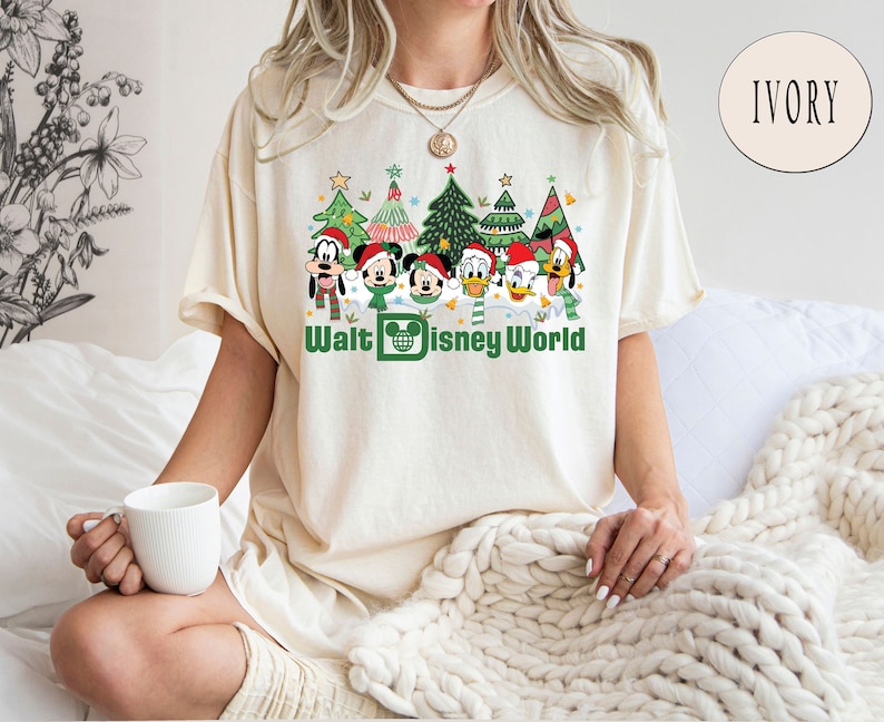 May include: A white t-shirt with a Christmas-themed design featuring Mickey Mouse and friends in front of Christmas trees. The text "Walt Disney World" is printed below the characters.