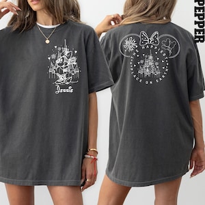 K&ouml;nnte beinhalten: Ein graues Oversize-T-Shirt mit einem wei&szlig;en Aufdruck von Mickey Mouse und dem Text "The Happiest Place on Earth" auf der R&uuml;ckseite. Die Vorderseite des Shirts zeigt einen wei&szlig;en Aufdruck von Minnie Mouse und den Text "Jessie".