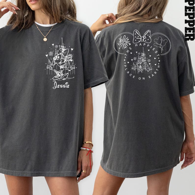 K&ouml;nnte beinhalten: Ein graues Oversize-T-Shirt mit einem wei&szlig;en Aufdruck von Mickey Mouse und dem Text "The Happiest Place on Earth" auf der R&uuml;ckseite. Die Vorderseite des Shirts zeigt einen wei&szlig;en Aufdruck von Minnie Mouse und den Text "Jessie".