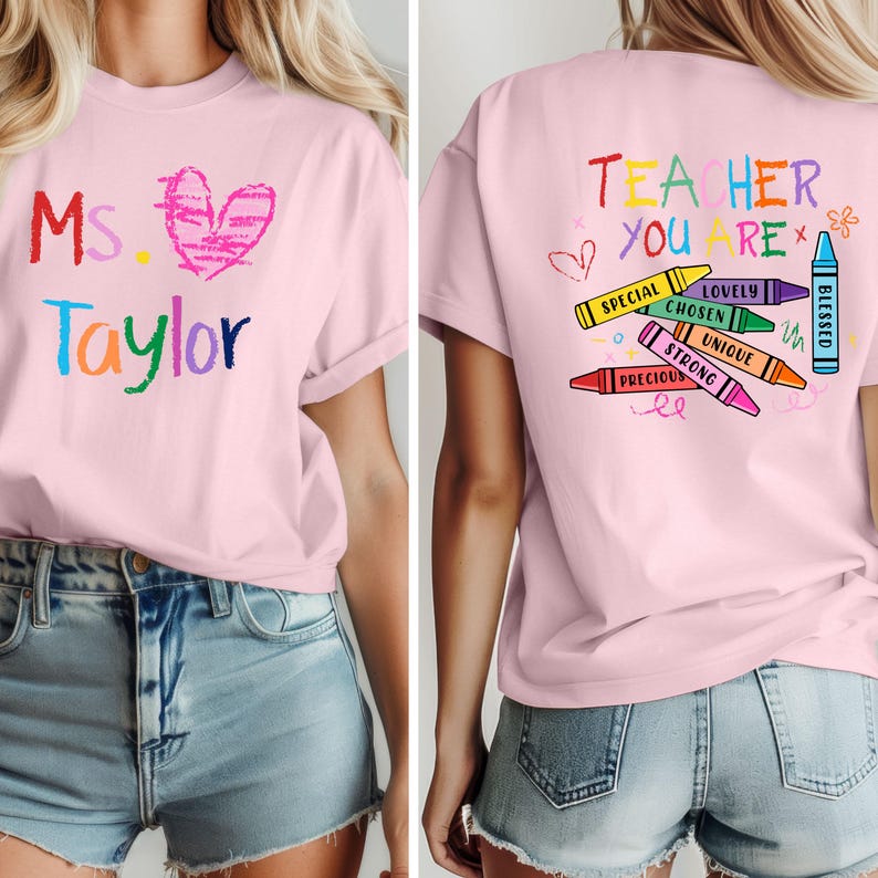 May include: Pink t-shirt with the name "Ms. Taylor" in colorful crayon-style lettering and a pink heart. The back of the shirt says "Teacher You Are" with crayon illustrations and words like "Special" and "Blessed".