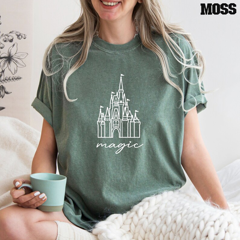 May include: A green t-shirt with a white outline of Cinderella's castle and the word "magic" underneath.