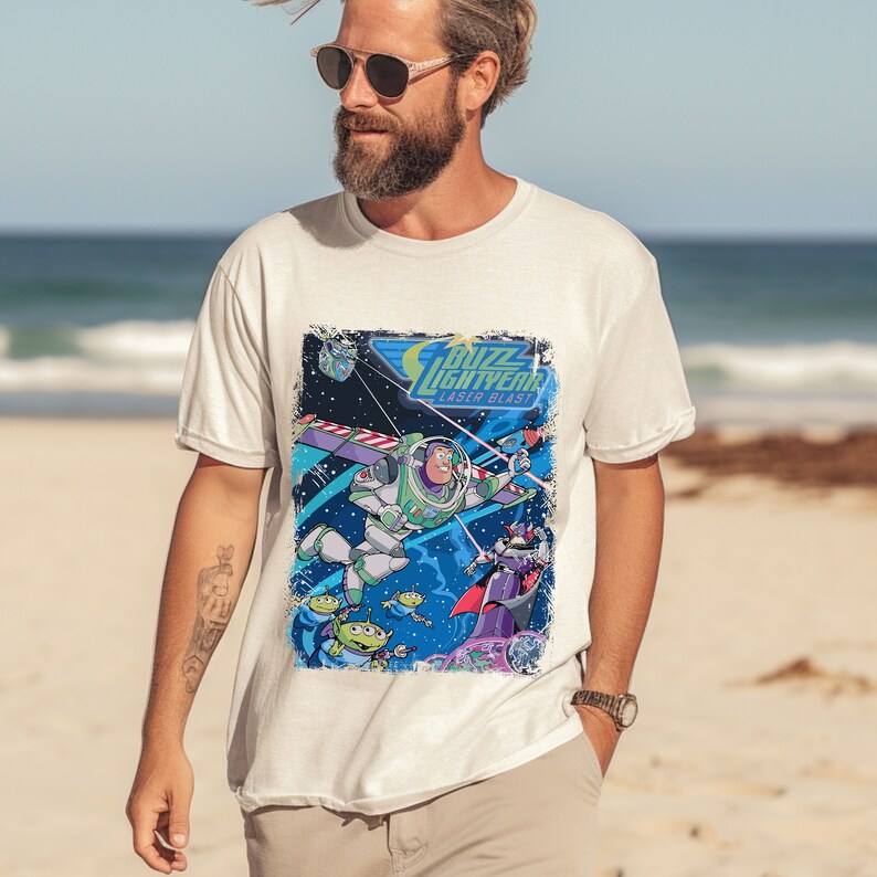 May include: White t-shirt with a graphic print of Buzz Lightyear from the Toy Story franchise. The graphic features Buzz Lightyear in his space ranger suit, flying through space with a laser blast. The text "Buzz Lightyear Laser Blast" is printed above the graphic.