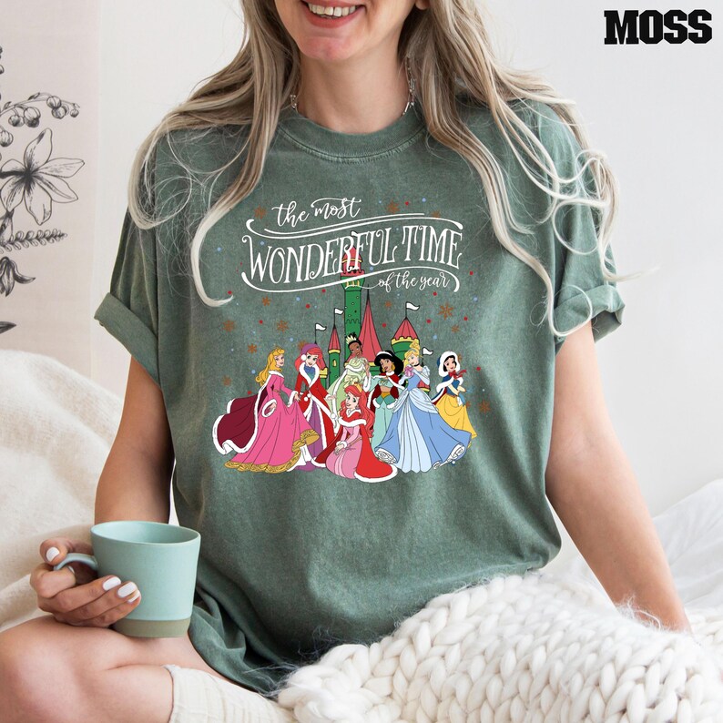 May include: Green t-shirt with a white graphic of Disney princesses in front of a castle. The text reads "the most wonderful time of the year".