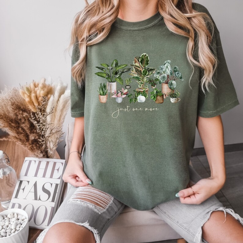 May include: A green t-shirt with a graphic of potted plants and the text "just one more".