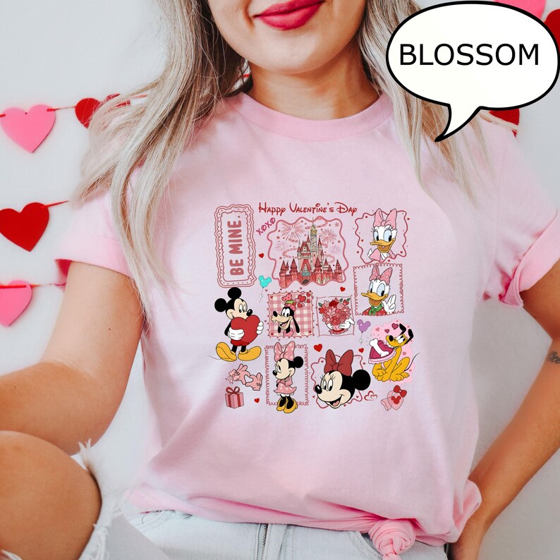 May include: Pink t-shirt featuring a Valentine's Day design with Disney characters. The design includes Mickey and Minnie Mouse, Donald Duck, and Pluto, along with the text "Happy Valentine's Day" and "Be Mine."