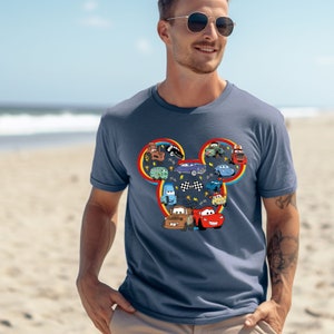 Puede incluir: Una camiseta azul marino con una silueta de Mickey Mouse formada por personajes de la franquicia de pel&iacute;culas Cars. La silueta est&aacute; delineada en rojo, amarillo y azul.