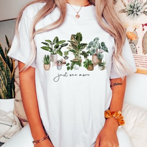 May include: White t-shirt with a watercolor illustration of potted plants and the text "just one more".