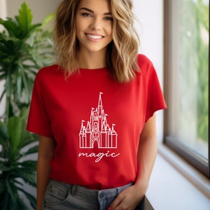 May include: A red t-shirt with a white outline of Cinderella's castle and the word "magic" underneath.