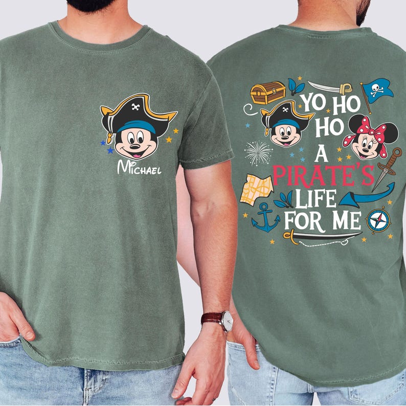 May include: Two green t-shirts with a pirate theme. One shirt features Mickey Mouse and Minnie Mouse dressed as pirates with the text "Yo ho ho a pirate's life for me". The other shirt features Mickey Mouse dressed as a pirate with the text "Michael".