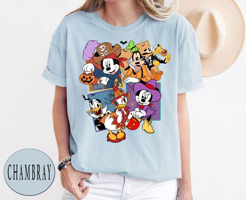 K&ouml;nnte beinhalten: Hellblaues T-Shirt mit einem Grafikdruck von Mickey Mouse, Minnie Mouse, Donald Duck, Goofy und Pluto in Halloween-Kost&uuml;men. Die Figuren halten K&uuml;rbisse und S&uuml;&szlig;igkeiten.