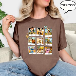 Puede incluir: Camiseta marr&oacute;n con un gr&aacute;fico de personajes de Disney vestidos como exploradores de safari. Los personajes incluyen Mickey Mouse, Minnie Mouse, Pluto, Goofy, Daisy Duck, Donald Duck, Stitch y Lilo & Stitch. El texto "Espresso" est&aacute; en un bocadillo de di&aacute;logo en la esquina superior derecha de la imagen.