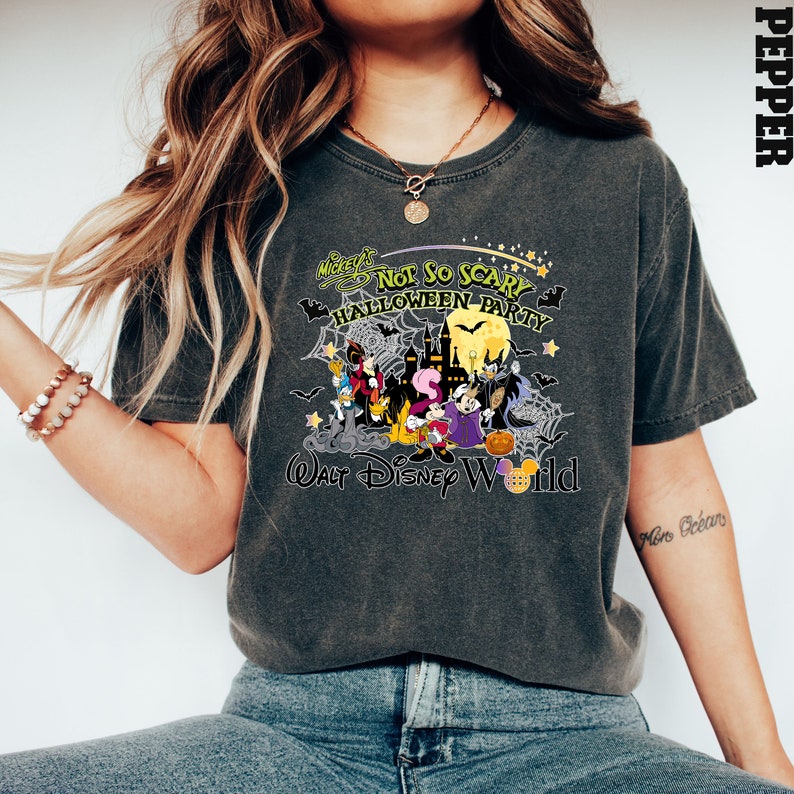 May include: A dark gray t-shirt with a graphic print of Mickey Mouse and friends dressed in Halloween costumes. The text on the shirt reads "Mickey's Not So Scary Halloween Party" and "Walt Disney World".