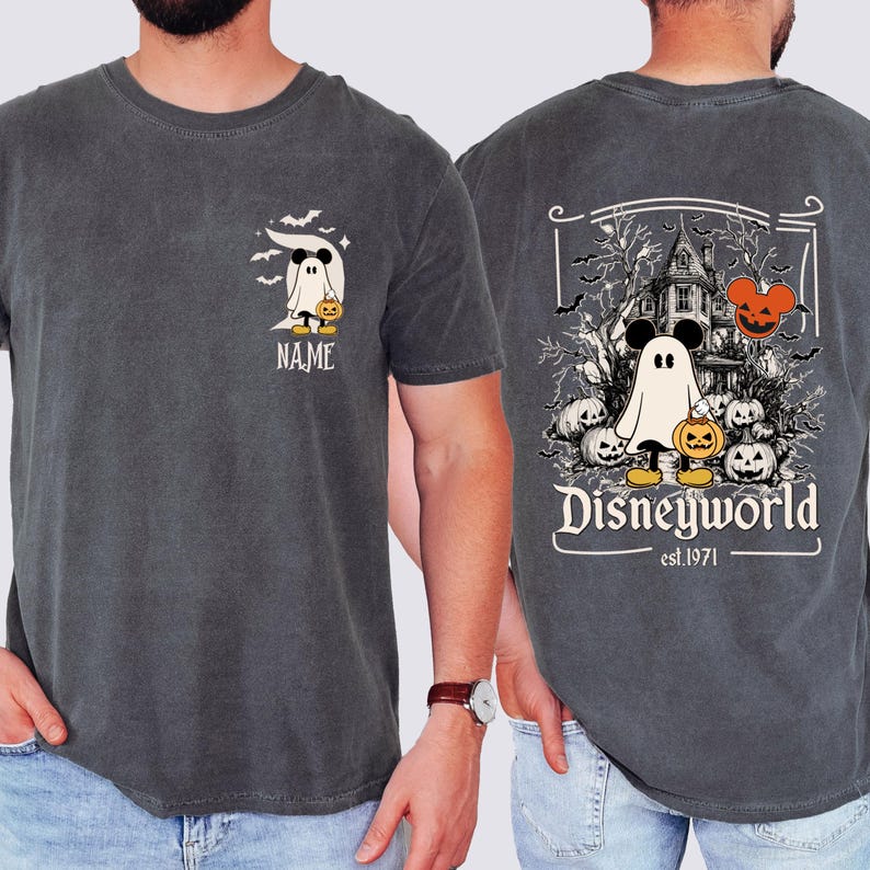 Pu&ograve; includere: T-shirt grigio scuro con un design a tema Halloween. La parte anteriore mostra un personaggio fantasma con una zucca e la parola "NAME". Il retro presenta una scena di casa infestata con la scritta "Disneyworld est.1971".