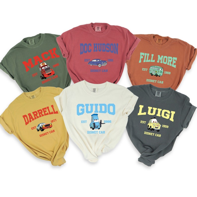 Puede incluir: Seis camisetas de diferentes colores con personajes y nombres de Cars. Las camisetas est&aacute;n todas dobladas y dispuestas sobre un fondo blanco. Los personajes incluyen Mack, Doc Hudson, Fill More, Darrell, Guido y Luigi.