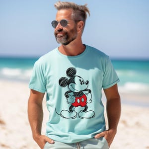 May include: A light blue t-shirt with a black and white sketch of Mickey Mouse wearing red shorts.