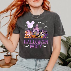 May include: A black t-shirt with a purple graphic of Mickey Mouse and friends in front of the Cinderella Castle at Disney World. The text "Mickey's Not So Scary Halloween Party" is printed in purple below the graphic.